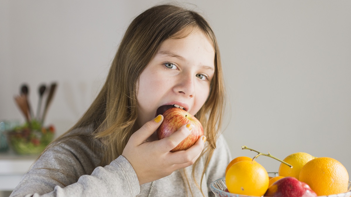 Девочка ест яблоко